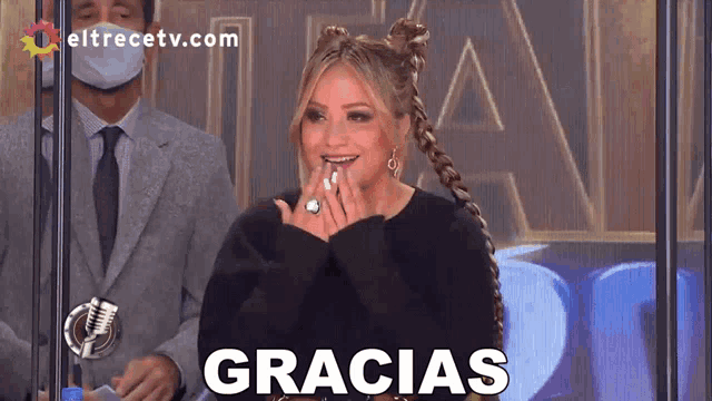a woman sitting in front of a microphone with the word gracias written on the screen
