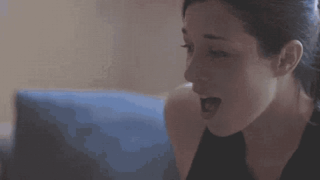a woman is sitting on a couch with her mouth open .