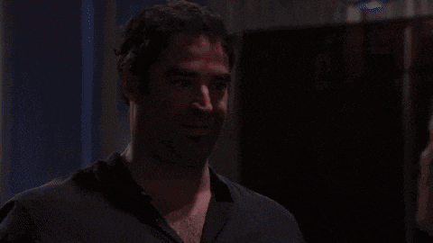 a man in a red shirt smiles in a dark room