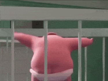 a pink stuffed animal is standing in a white cage behind bars .