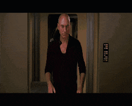 a bald man in a red shirt is standing in front of a door