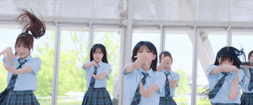 a group of girls in school uniforms and ties are dancing in a room