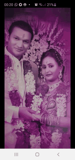 a man and a woman are posing for a picture with a purple background and the time of 01:20