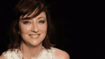 a woman in a white dress is smiling and looking at the camera against a black background .