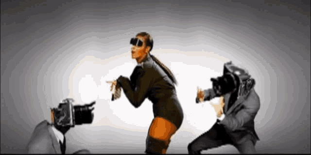 a woman wearing sunglasses is being photographed by a man with a camera
