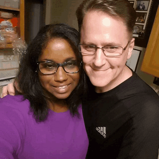 a man wearing an adidas shirt hugs a woman