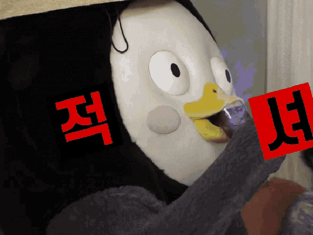a stuffed penguin holding a red sign with the letters jl on it