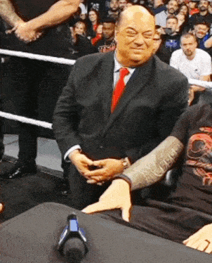 a man in a suit and tie holds another man 's hand in front of a crowd