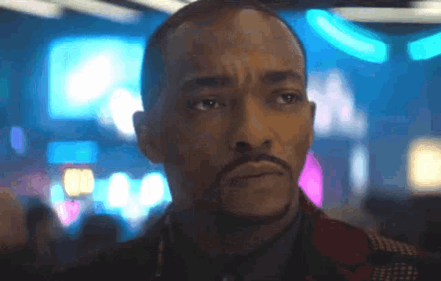 a man with a beard is looking at the camera with a blurry background .