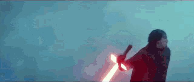 a person is holding a red light saber in their hand in the dark .