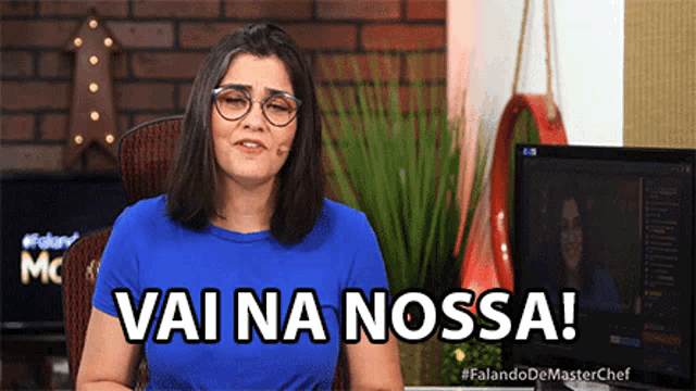 a woman in a blue shirt says vai na nossa in front of a monitor