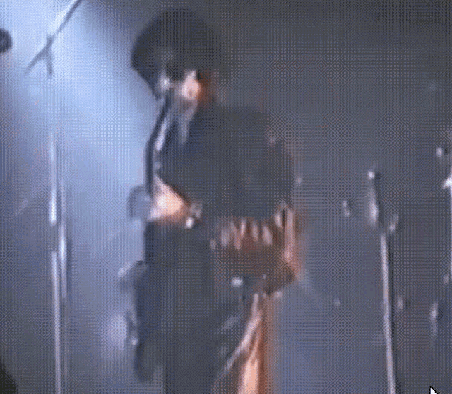a man playing a guitar and singing into a microphone on a stage