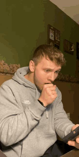 a man wearing a grey nike hoodie is looking at his phone