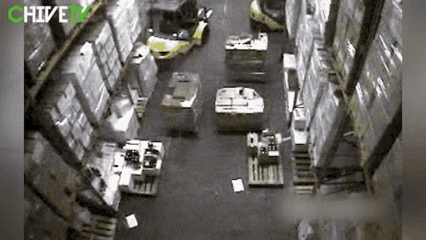 a forklift is driving through a warehouse filled with lots of boxes and pallets .