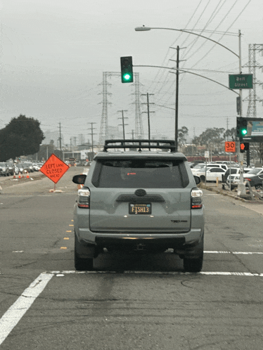 a car is driving down a street with a sign that says " left lane closed "