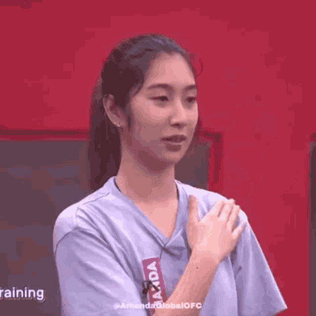 a woman in a blue shirt is clapping her hands in a gym .