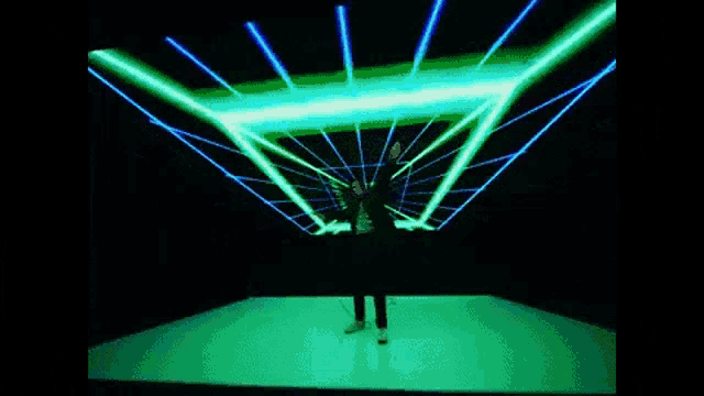 a man is dancing in a dark room with green and blue lights