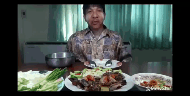 a man is sitting at a table with plates of food and a bowl of water