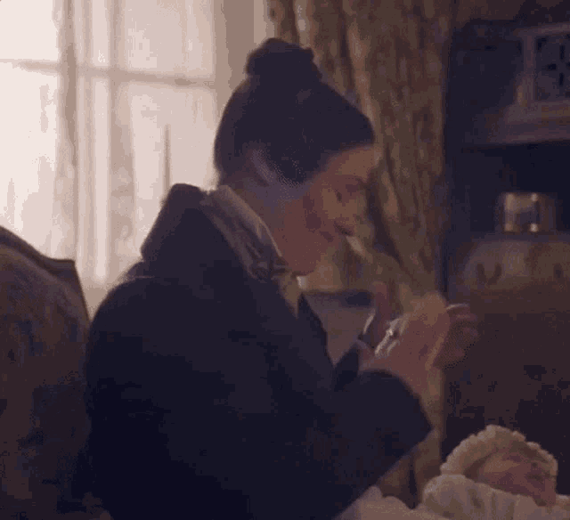 a woman is sitting on a couch holding a baby and clapping her hands