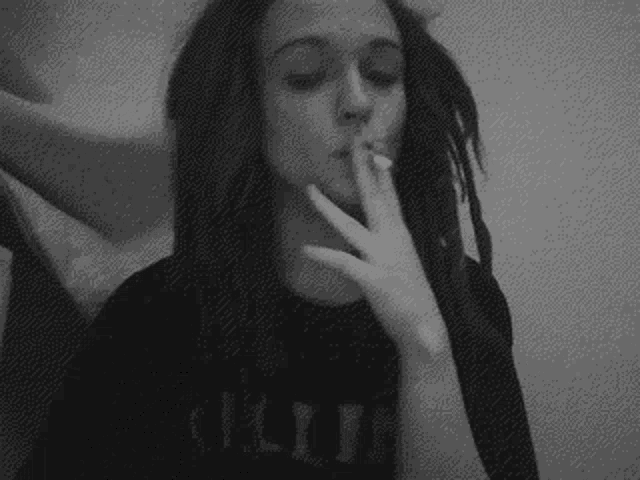 a black and white photo of a woman smoking a cigarette .