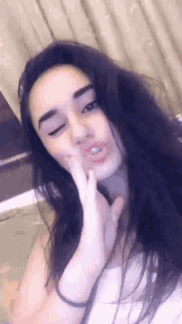 a woman with long hair is making a funny face with her hand on her face .