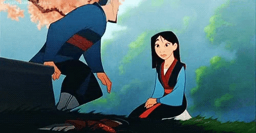 a man is kneeling down next to a woman sitting on the ground in a field .
