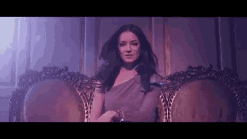 a woman in a purple dress is sitting on a chair .