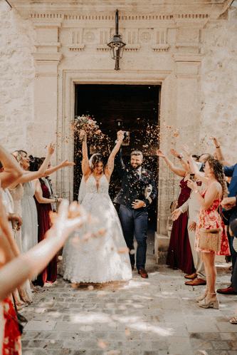 a bride and groom are surrounded by people throwing confetti