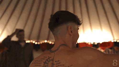 a man with a tattoo on his back has the letter s on his back