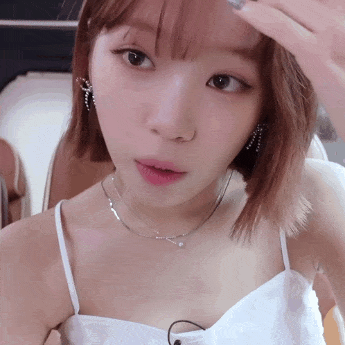 a close up of a woman wearing a white tank top and earrings