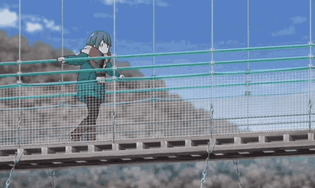 a person walking across a bridge with a green fence