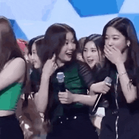 a group of girls are standing next to each other holding microphones and laughing .