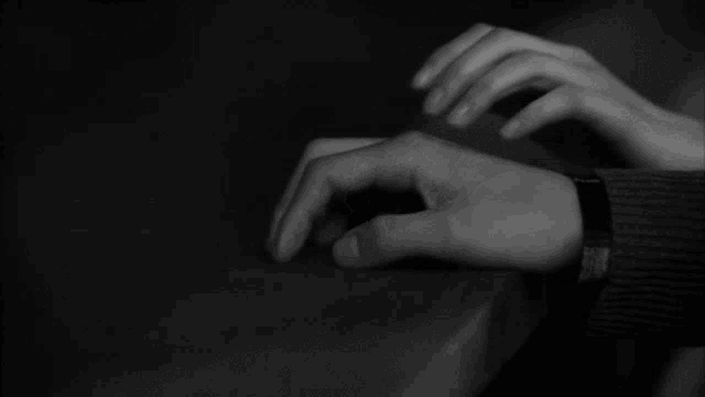 a black and white photo of a person holding another person 's hand .