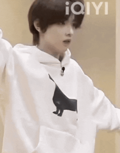 a young man is wearing a white hoodie with a black cat on the front .