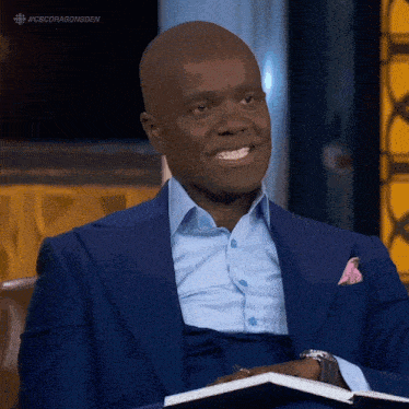 a man in a suit is smiling while holding a notebook