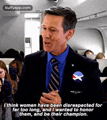 a man in a suit and tie is talking to a group of people on a plane .