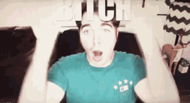 a man in a blue shirt with the word bitch written on his head