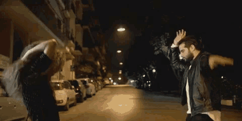 a man and woman are standing on a street at night .