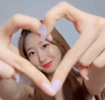 a woman is making a heart shape with her hands and smiling .