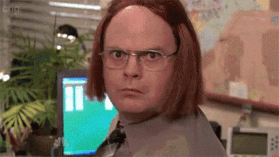 a man wearing glasses and a wig is sitting in front of a computer in an office .
