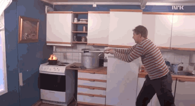 a man stands in a kitchen with a pot on the stove and a sign that says nk