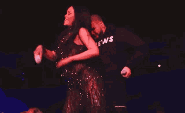 a man and a woman are standing next to each other on a stage and laughing .
