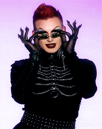 a drag queen wearing a black outfit and gloves covering her eyes with her hands