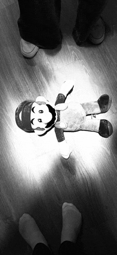 a black and white photo of a stuffed mario laying on the floor