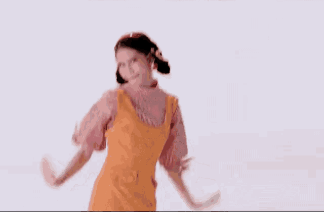 a woman in an orange dress is dancing with her arms outstretched .