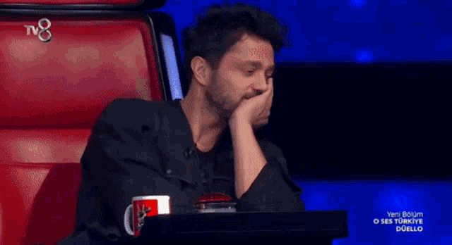 a man sits in a red chair with a tv8 logo on the bottom