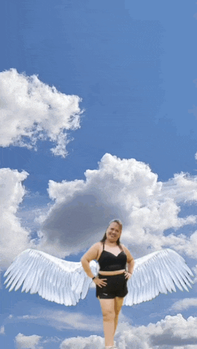 a woman with white angel wings stands in the clouds