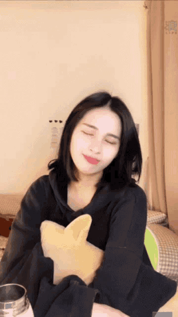 a woman with her eyes closed holds a stuffed animal in her arms