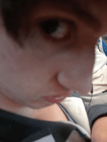 a close up of a person 's face with a blue shirt in the background