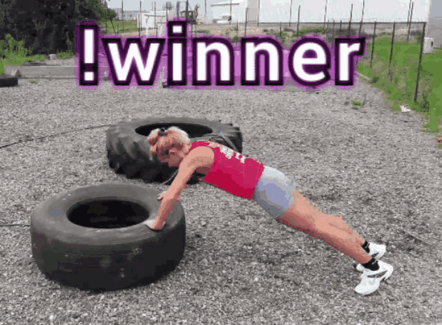 a woman is doing push ups in front of a tire with the words winner above her